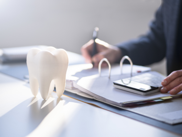 tooth sitting next to binder with dental payment information