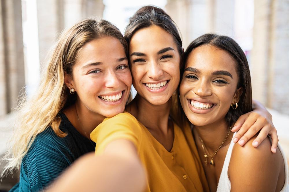 three woman smiling while taking a selfie