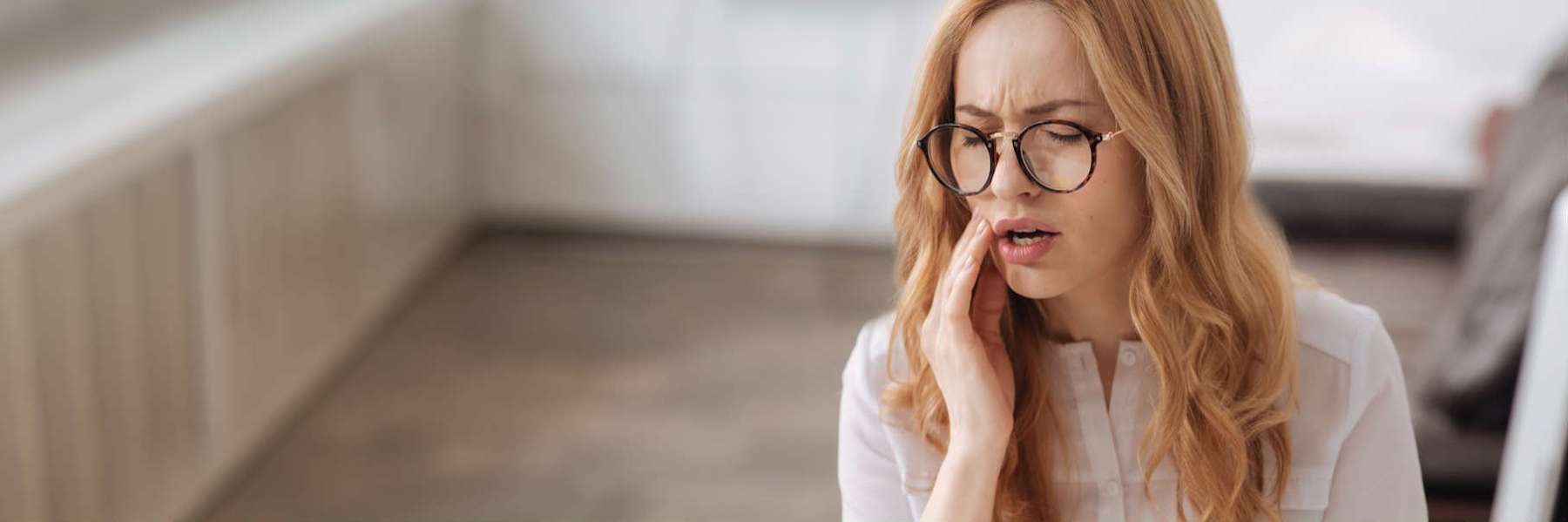 renton woman putting hand on her cheek during a dental emergency