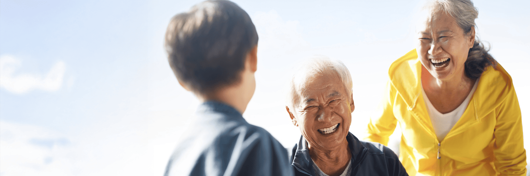 older man and woman laughing with their grandchild